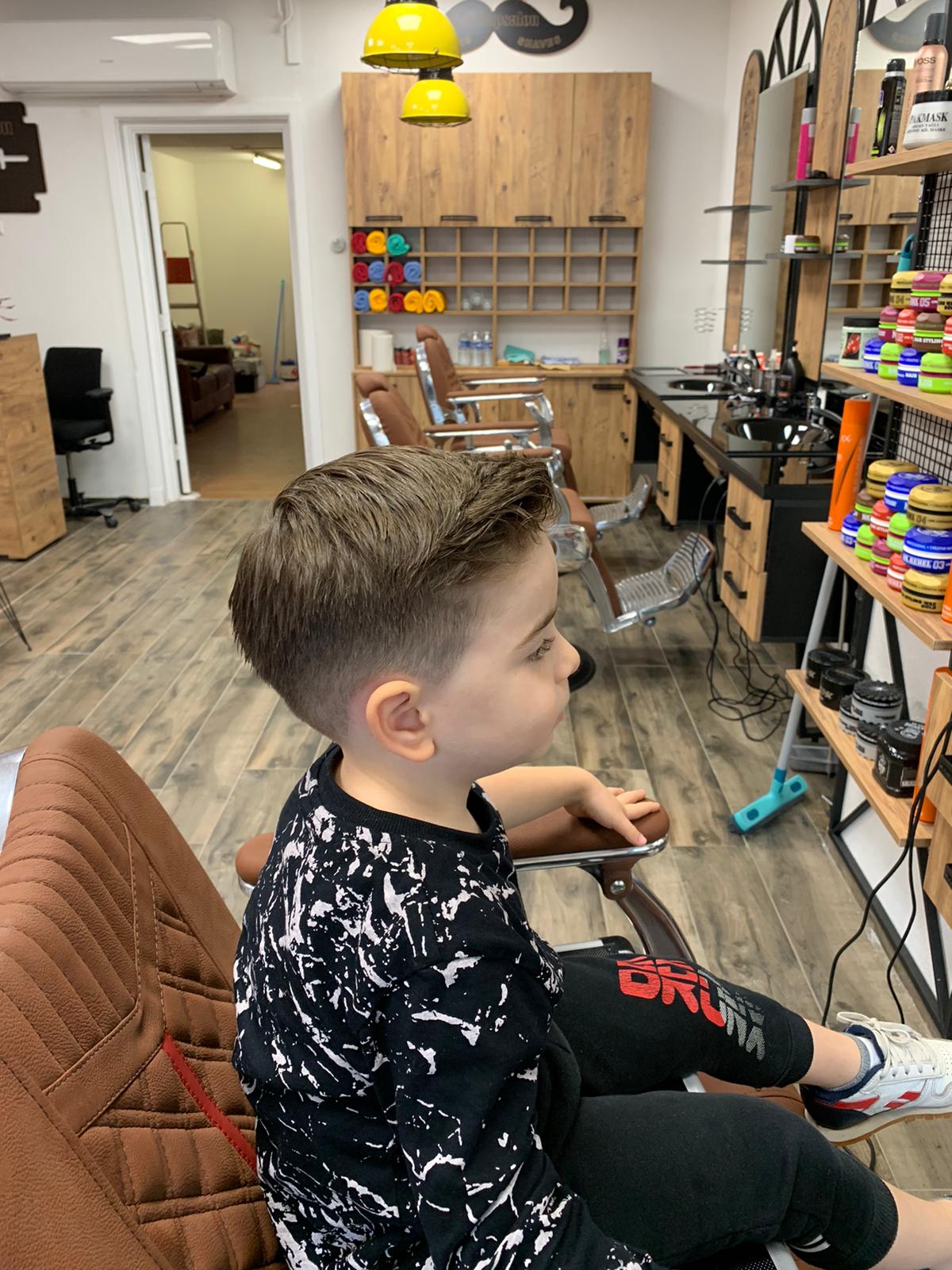 Jongen in de kappersstoel met een vers geknipte fade, in profiel